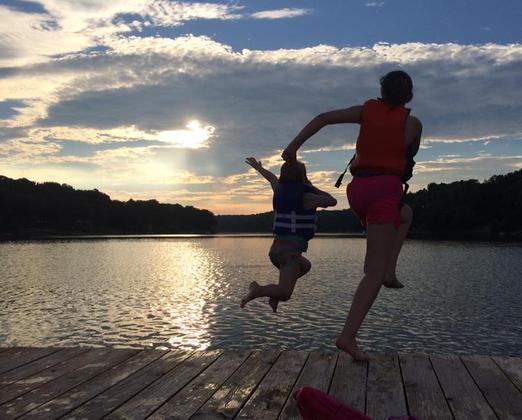 Two People Jumping over Lake Avalon from Deck