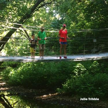 Three People Walking on a Foot Bridge