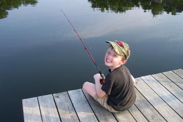 A Smiling Boy on Deck with a Fishing Rod