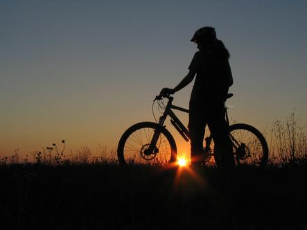 A Biker Standing with Sun in the Background